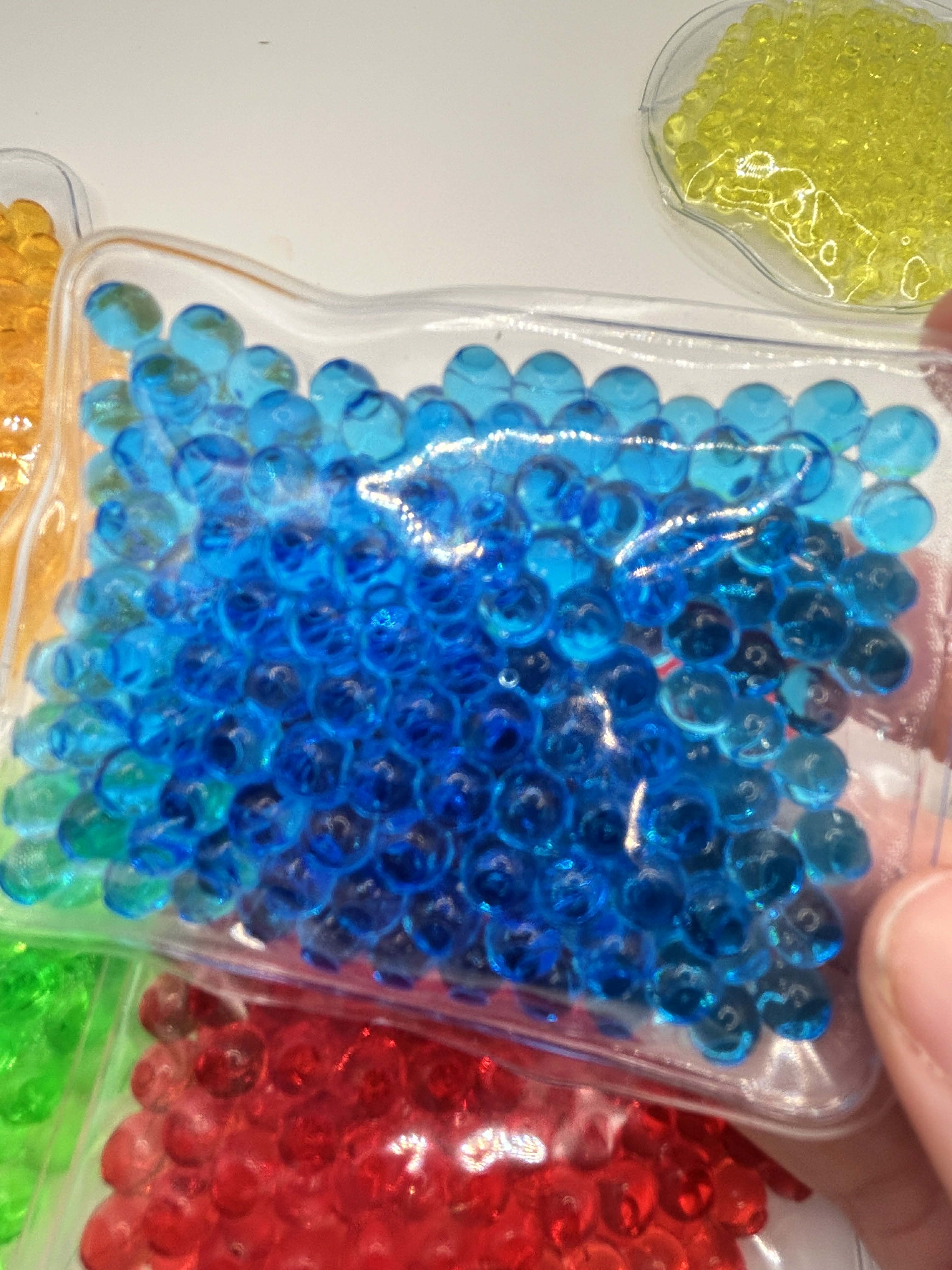 Six different water bead sensory shapes in vibrant colours for neurodivergent children