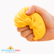 Hand holding a yellow brain-shaped stress reliever with 'Divergent Den' logo.
