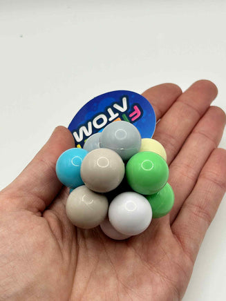 Fidget Atom close-up in a hand showing multi-coloured tactile buttons for stress relief and focus
