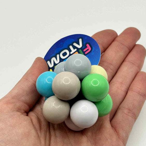 Fidget Atom close-up in a hand showing multi-coloured tactile buttons for stress relief and focus