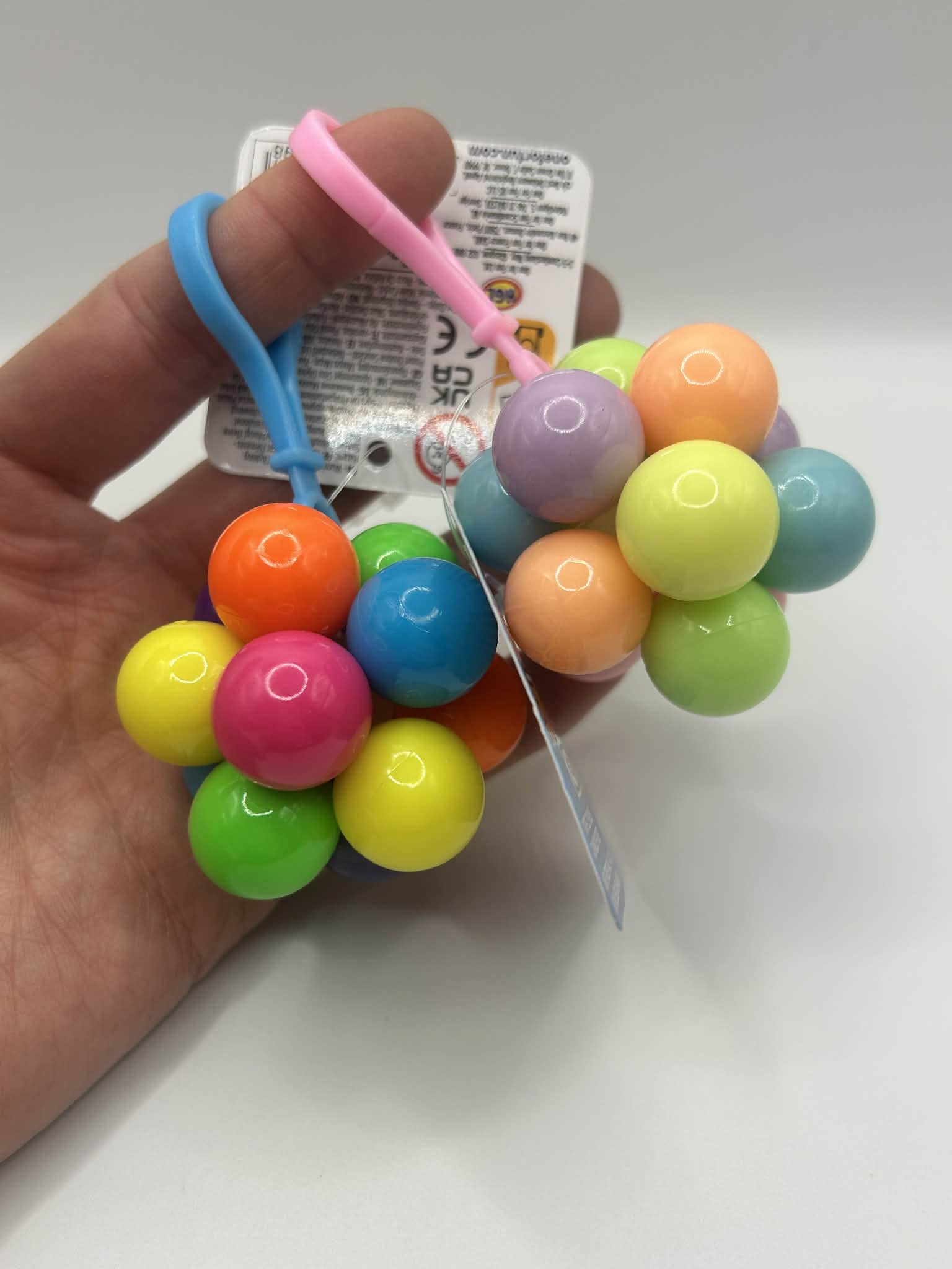 Fidget Atom close-up in a hand showing multi-coloured tactile buttons for stress relief and focus