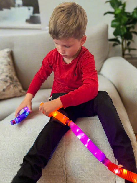 A child playing with the Sensory Light Up Pop Tubes connecting them together – flexible fidget toy with LED lights for neurodivergent children | The Divergent Den