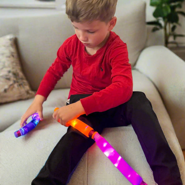 A child playing with the Sensory Light Up Pop Tubes connecting them together – flexible fidget toy with LED lights for neurodivergent children | The Divergent Den