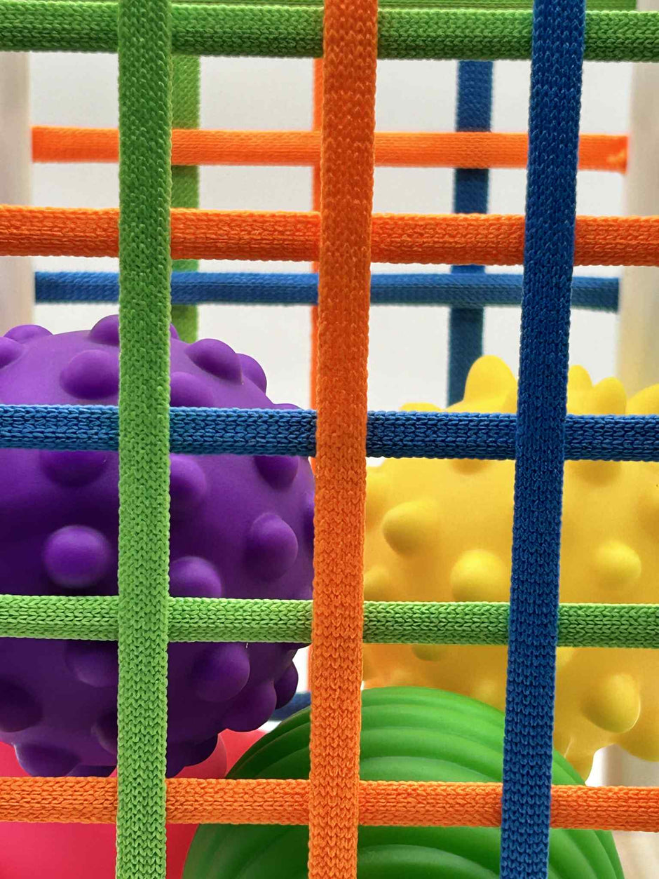 Close-up of Sensory Seekers Sorting Box showing 4 textured balls and soft ribbon openings for sensory play